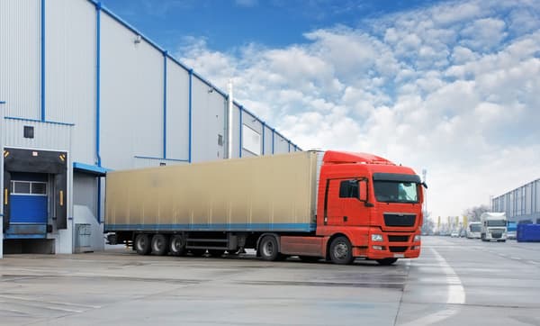 Red freight truck parked at a warehouse loading dock