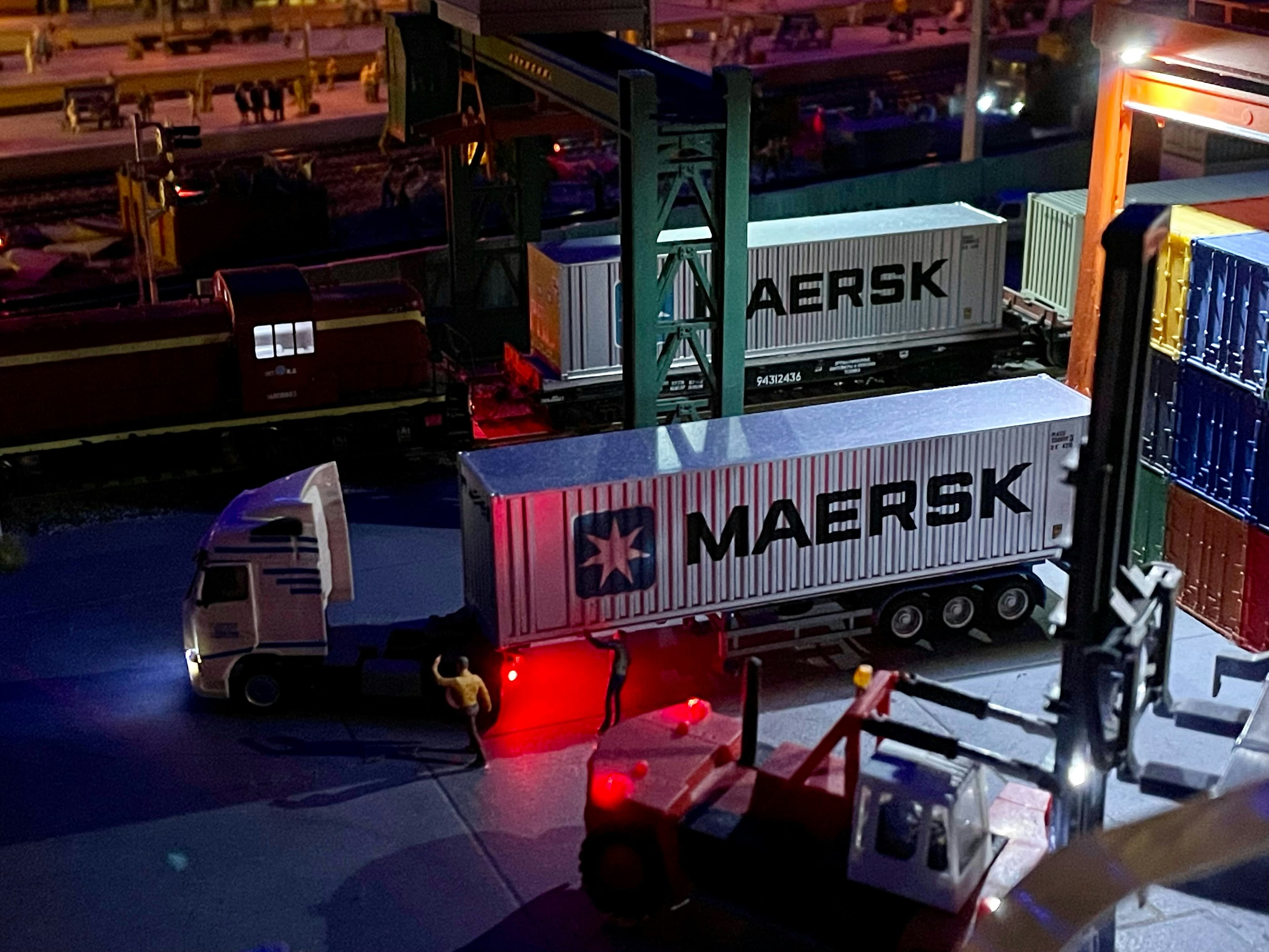 Container trucks moving through a port terminal at night